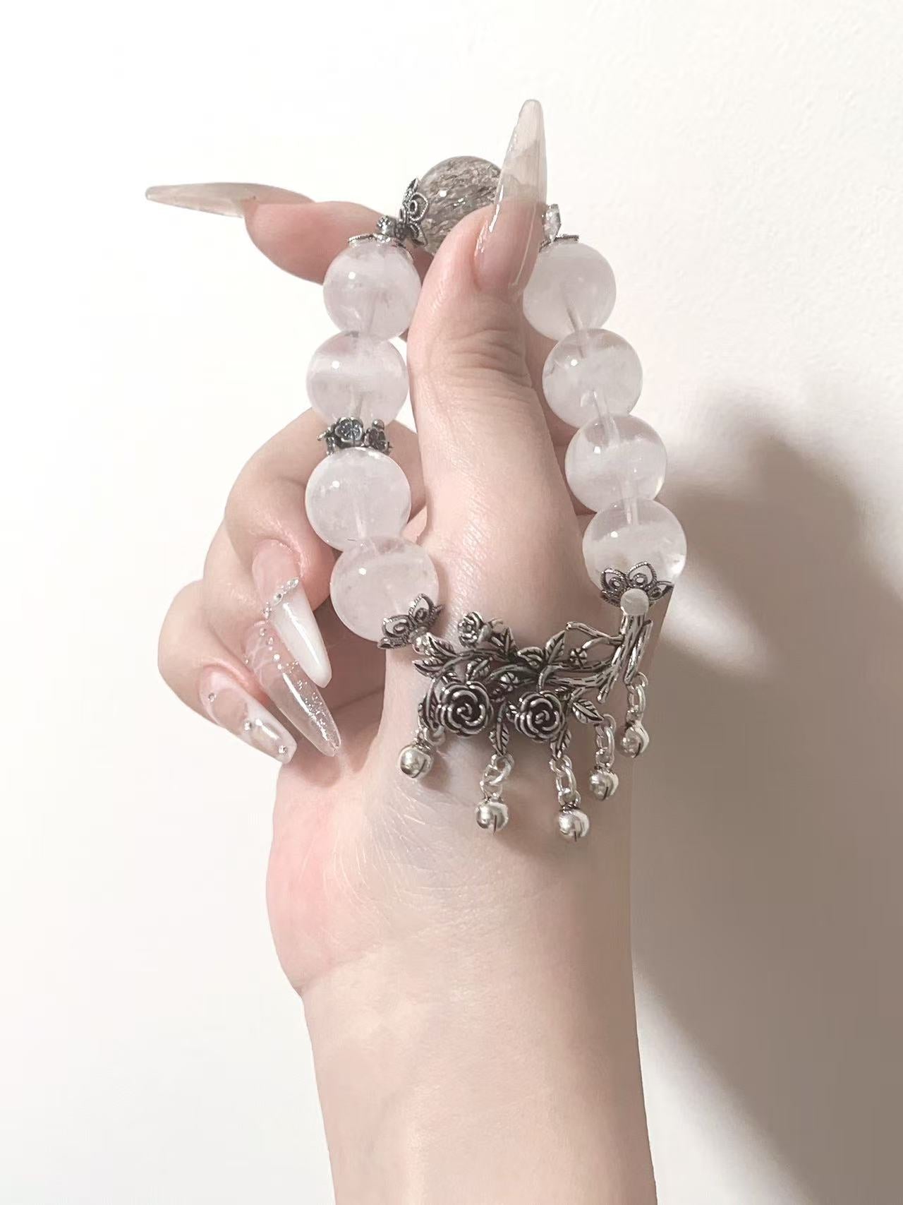 White crystal bracelet with silver floral charm held in hand