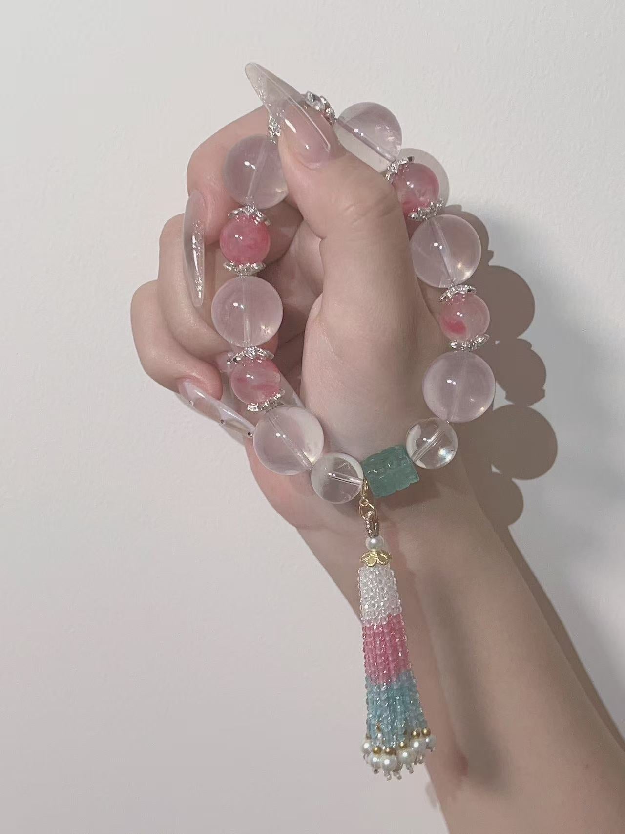 Pink and green crystal bracelet with tassel charm worn on wrist